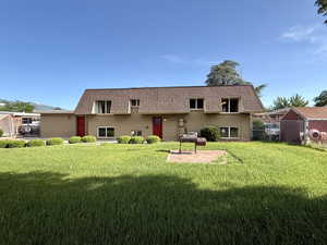 Back of property with mansard roof, brick siding, and a shingled roof