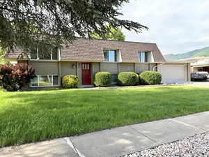 View of front of property featuring a front yard, a garage, and mansard roof