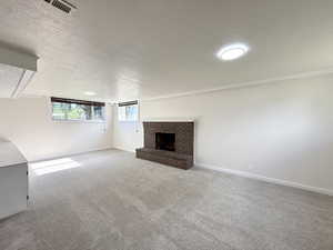 Unfurnished living room featuring a textured ceiling, carpet floors, a fireplace, and baseboards