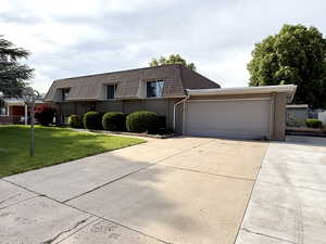 Front facade with brick siding, a front yard, mansard roof, and an attached garage