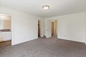 Unfurnished bedroom with carpet, baseboards, and ensuite bath