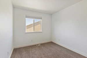 Spare room featuring carpet flooring and baseboards