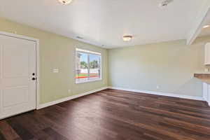 Unfurnished living room with dark wood finished floors and baseboards