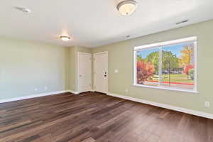 Unfurnished room featuring baseboards, dark wood-style floors, and a smoke detector