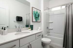 Bathroom featuring vanity, shower / bathtub combination with curtain, and toilet