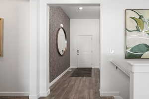 Foyer entrance featuring wallpapered walls, baseboards, and wood finished floors