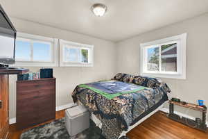 Bedroom with multiple windows, baseboards, and wood finished floors.