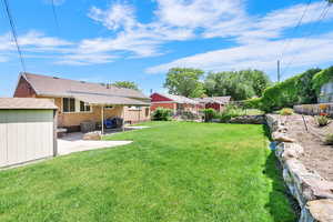 View of yard with a patio area, central AC unit, and included shed.
