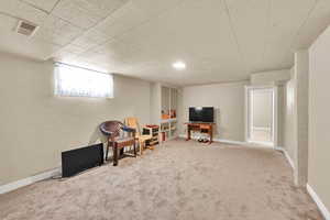 Sitting room with carpet floors, baseboards, and a textured walls.
