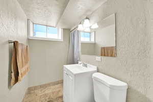 Bathroom with a textured wall and ceiling with vanity.