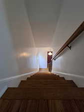 Stairs featuring wood finished floors and vaulted ceiling