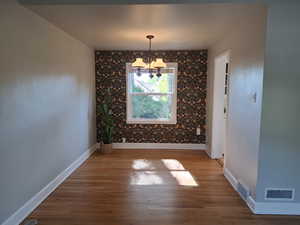 Unfurnished dining area with a chandelier and wood finished floors