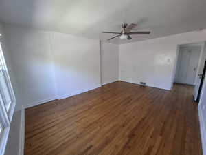 Empty room with dark wood finished floors and ceiling fan