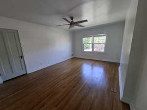 Spare room featuring ceiling fan and dark wood-type flooring