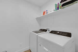 Washroom featuring independent washer and dryer, baseboards, and light wood finished floors