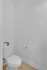 Bathroom with baseboards, toilet, and wood finished floors