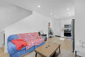 Living room with light wood finished floors and recessed lighting