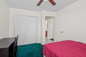 Carpeted bedroom with ceiling fan and a closet