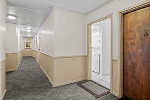 Hallway with estacked washer and dryer and carpet