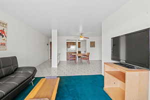 Living area featuring a ceiling fan and tile patterned floors