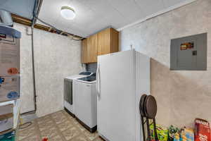 Laundry area with cabinet space, washing machine and dryer, electric panel, and light floors