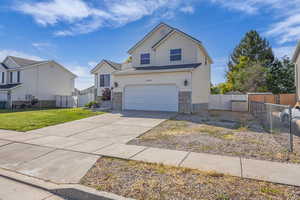 View of front of home with concrete driveway, a garage, a gate, and stone siding