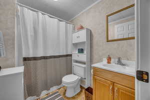 Bathroom with vanity, toilet, crown molding, and curtained shower