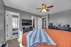 Bedroom featuring carpet flooring, baseboards, ceiling fan, and ensuite bath