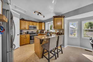 Kitchen with appliances with stainless steel finishes, vaulted ceiling, plenty of natural light, stone countertops, and decorative backsplash
