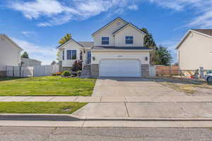 View of front of home featuring driveway, an attached garage, a gate, and stone siding