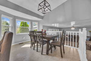 Dining area featuring plenty of natural light, baseboards, vaulted ceiling, a chandelier, and ceiling fan