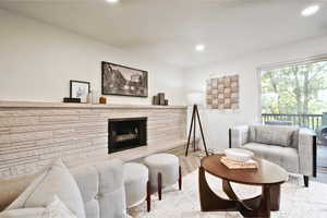 Living room with a stone fireplace, recessed lighting, baseboards, and wood finished floors
