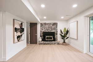 Living area featuring a fireplace, wood finished floors, baseboards, and recessed lighting