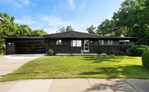 Ranch-style home featuring concrete driveway, a garage, a front lawn, and brick siding
