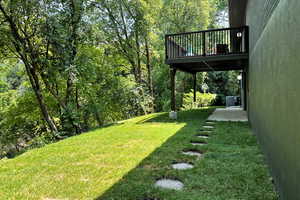 View of green lawn featuring central AC unit and a wooden deck