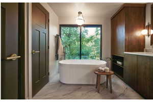 Bathroom featuring marble look tiles, a freestanding tub, vanity, and a textured ceiling