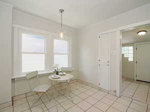 Dining space featuring light tile patterned floors and crown molding