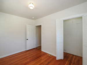 Unfurnished bedroom with hardwood / wood-style floors, a closet, baseboards, and ornamental molding