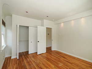 Unfurnished bedroom featuring wood finished floors, a closet, baseboards, and recessed lighting