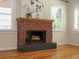 Detailed view of wood finished floors, a fireplace, and baseboards