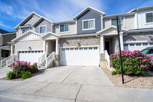View of front of home featuring concrete driveway, stone siding, board and batten siding, stucco siding, and an attached garage