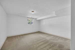 Unfurnished room with carpet, baseboards, and a textured ceiling