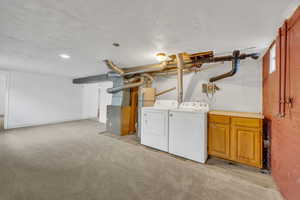 Laundry room with washer and dryer, cabinet space, light carpet, and heating unit