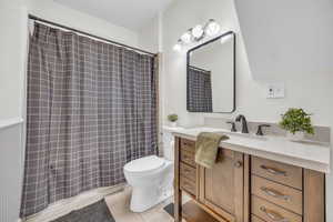 Full bathroom with toilet, vanity, tile patterned floors, and a shower with curtain