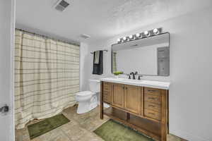 Bathroom featuring toilet, vanity, and curtained shower