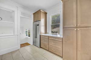 Kitchen featuring high end fridge, healthy amount of natural light, light countertops, ornamental molding, and light tile patterned floors
