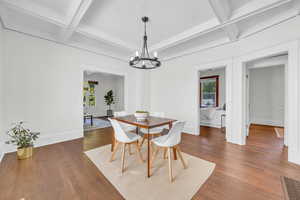Dining area with coffered ceiling, healthy amount of natural light, a chandelier, dark wood-style floors, and beamed ceiling