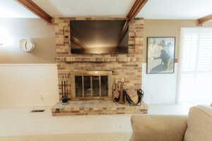 Living room featuring beam ceiling, carpet floors, and a fireplace