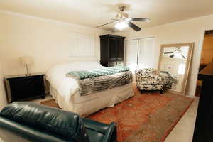 Carpeted bedroom featuring a closet, ornamental molding, and ceiling fan