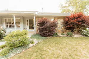 View of front of house with board and batten siding, stone siding, a front yard, and a porch